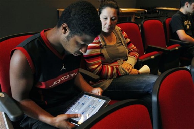Sophomore Lenny Thelusma, 16, checks out his new iPad as his mother, Tara Killion, looks on at Burlington High School in Burlington, Mass. Burlington is giving iPads this year to every one of its 1,000-plus high school students. Some classes will still have textbooks, but the majority of work and lessons will be on the iPads.